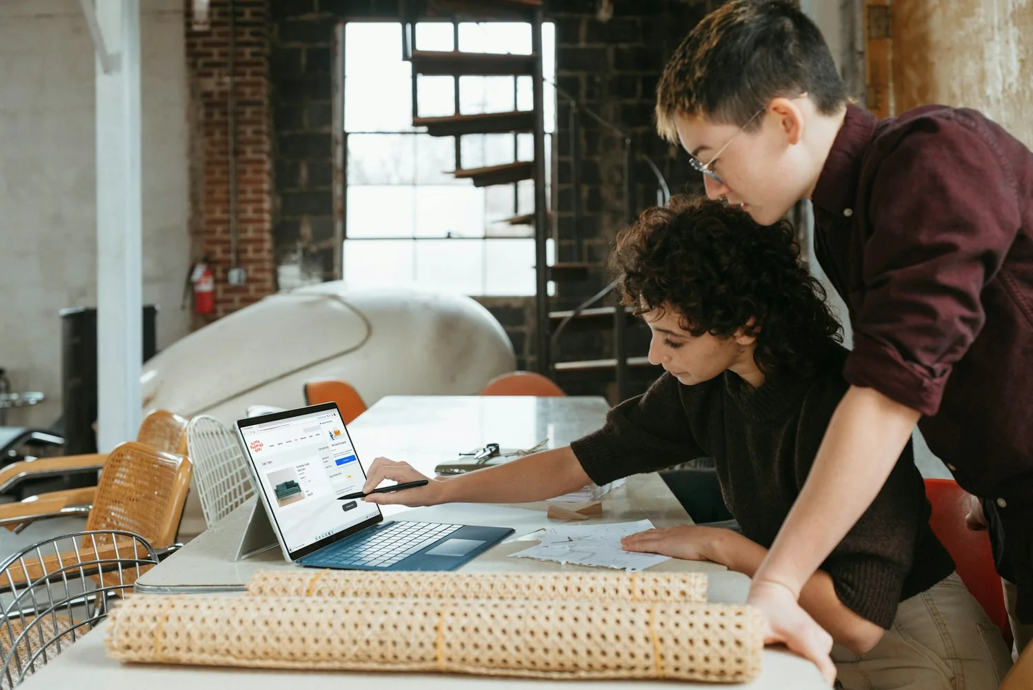 Duas pessoas comparando opções em um notebook